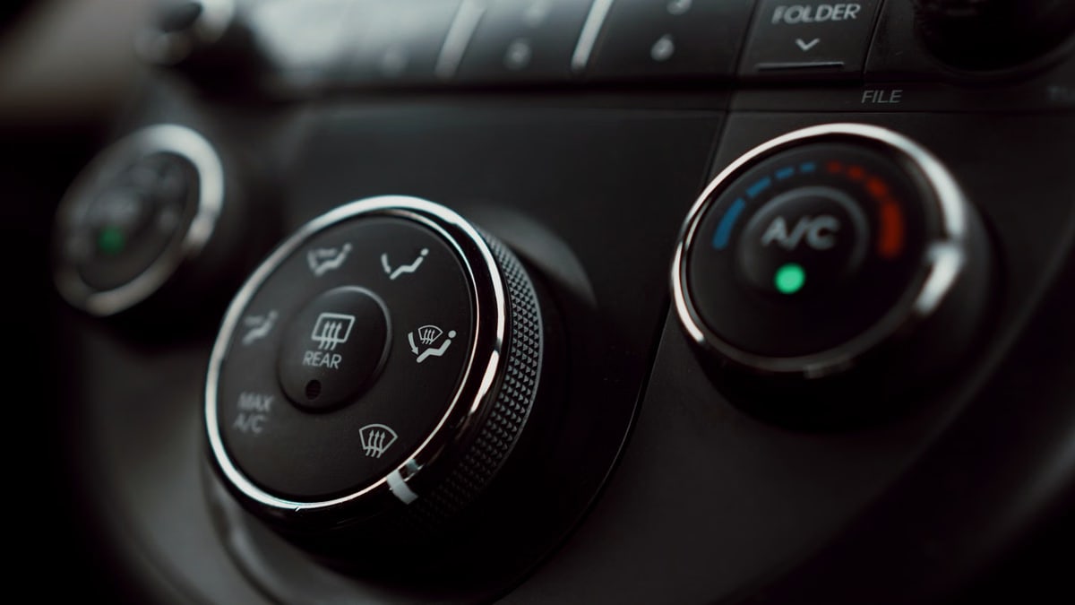 Detailed close-up of car dashboard air conditioning controls with focus on buttons and dials.